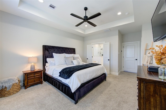 carpeted bedroom with ceiling fan, ensuite bathroom, and a tray ceiling