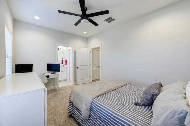 carpeted bedroom with ensuite bath and ceiling fan