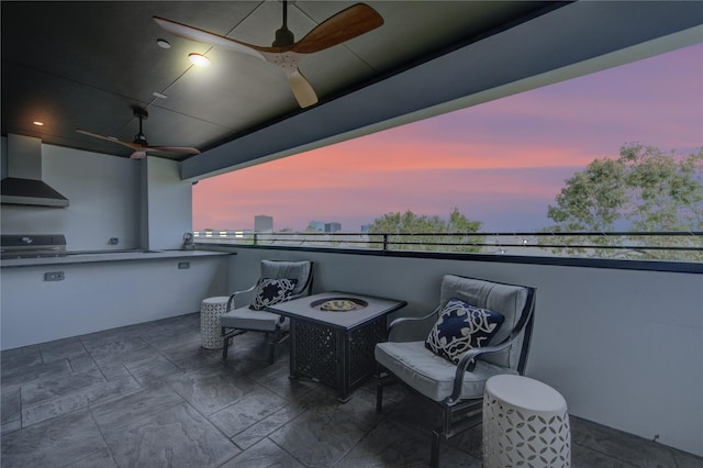 patio terrace at dusk featuring an outdoor kitchen, an outdoor fire pit, and area for grilling