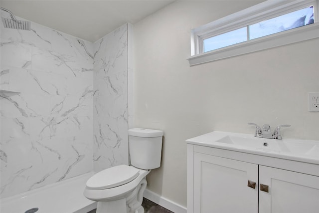 bathroom featuring vanity, a tile shower, and toilet