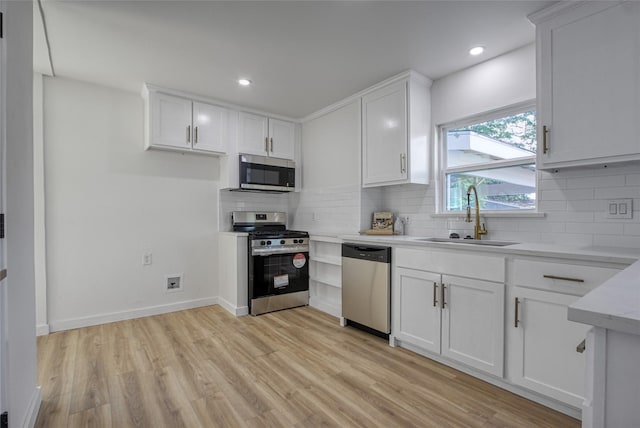 kitchen featuring stainless steel appliances, white cabinetry, sink, and light hardwood / wood-style flooring