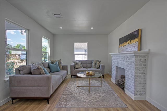 living room with a brick fireplace and light hardwood / wood-style flooring