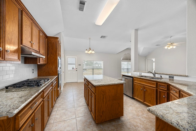 kitchen featuring lofted ceiling, sink, appliances with stainless steel finishes, hanging light fixtures, and a kitchen island