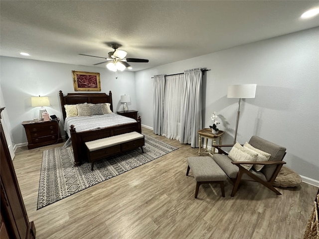 bedroom featuring ceiling fan, a textured ceiling, and light wood-type flooring