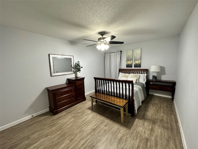 bedroom with ceiling fan, wood-type flooring, and a textured ceiling