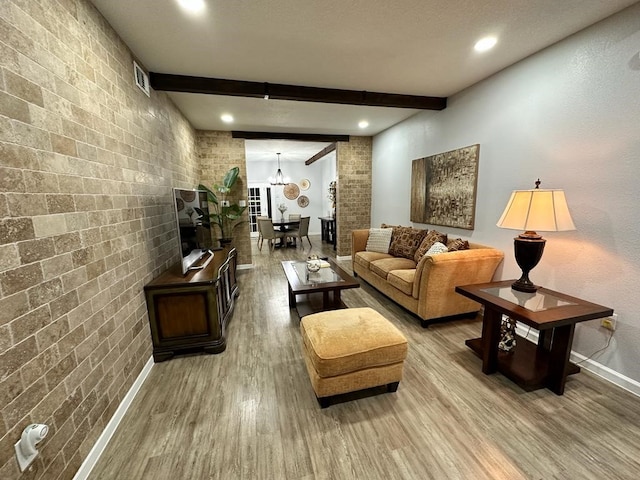 living room featuring hardwood / wood-style flooring, brick wall, and beamed ceiling