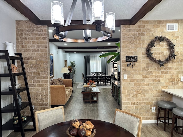 dining space featuring beamed ceiling, brick wall, hardwood / wood-style floors, and a textured ceiling