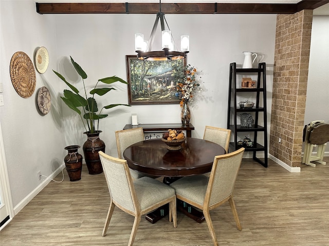 dining area featuring beamed ceiling, light hardwood / wood-style floors, and a chandelier