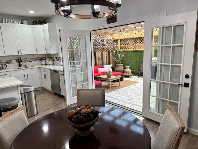 kitchen with sink, white cabinetry, tasteful backsplash, light wood-type flooring, and dishwasher