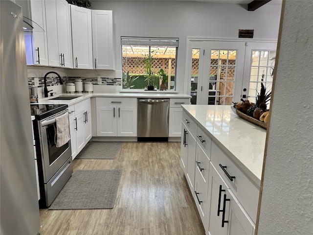 kitchen with sink, stainless steel appliances, light hardwood / wood-style floors, white cabinets, and decorative backsplash