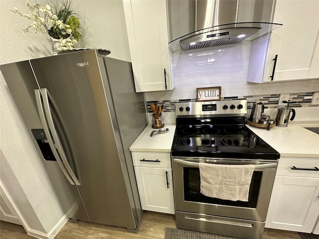 kitchen with appliances with stainless steel finishes, range hood, and white cabinets