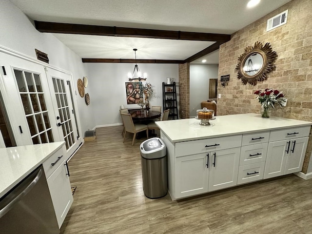 kitchen featuring beamed ceiling, white cabinetry, stainless steel dishwasher, pendant lighting, and hardwood / wood-style floors