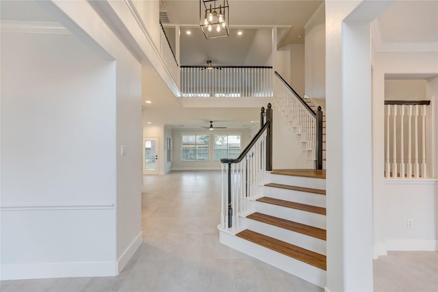 stairs featuring a towering ceiling, ornamental molding, tile patterned flooring, and a notable chandelier