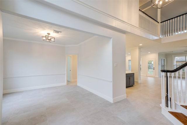 unfurnished room with a notable chandelier, ornamental molding, and a high ceiling