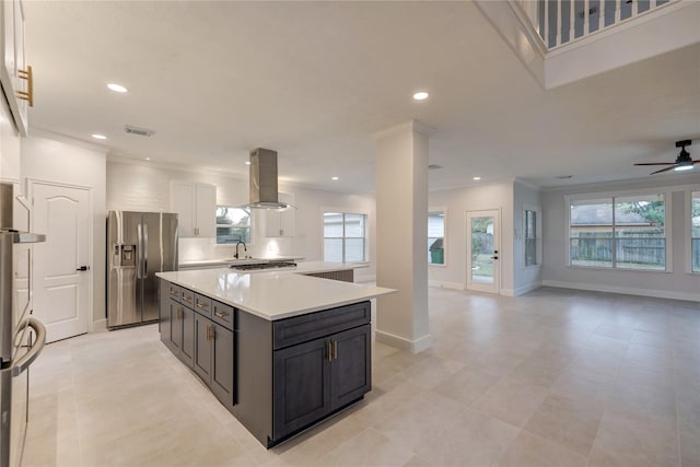 kitchen featuring appliances with stainless steel finishes, white cabinetry, a center island, island range hood, and ornamental molding