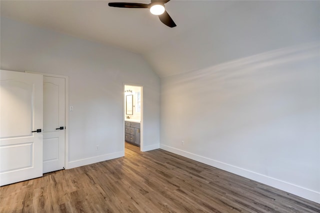 unfurnished bedroom with lofted ceiling, hardwood / wood-style floors, connected bathroom, and ceiling fan