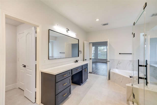 bathroom featuring vanity and independent shower and bath