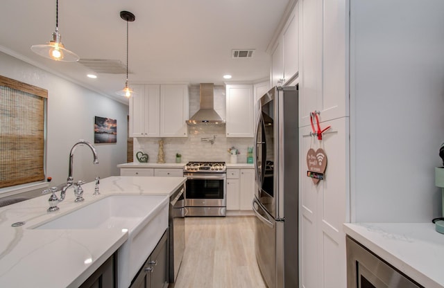 kitchen featuring pendant lighting, white cabinetry, stainless steel appliances, and wall chimney exhaust hood