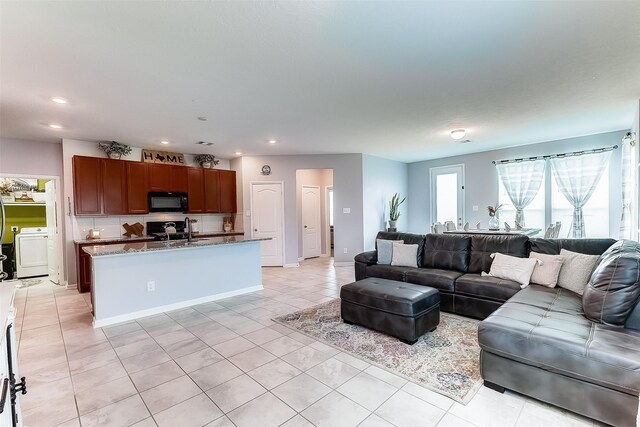 living room with washer / clothes dryer, sink, and light tile patterned flooring