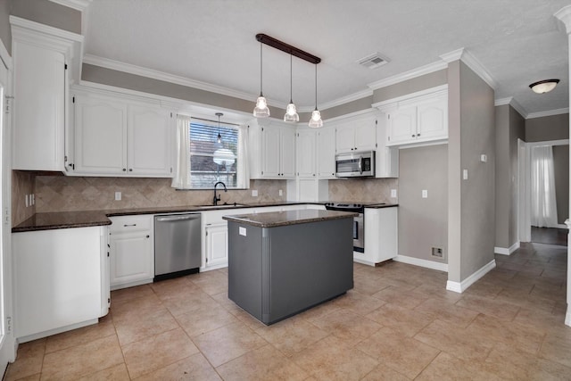 kitchen with stainless steel appliances, sink, a kitchen island, and white cabinets