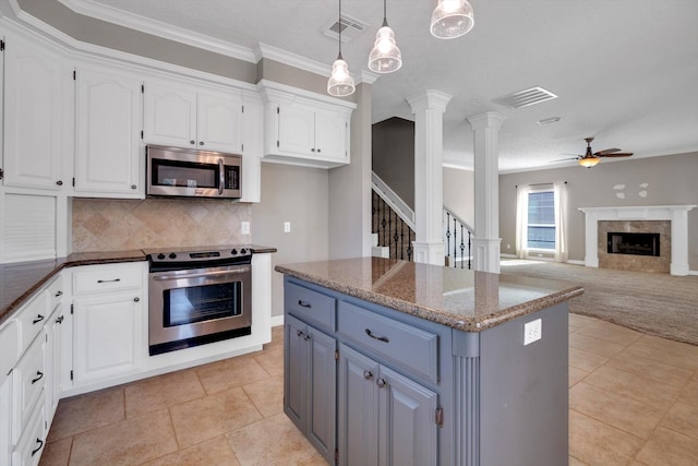 kitchen with hanging light fixtures, appliances with stainless steel finishes, white cabinets, and dark stone counters