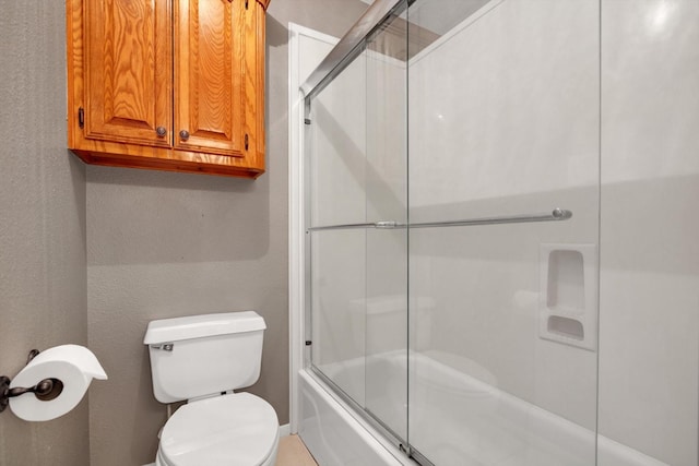 bathroom featuring bath / shower combo with glass door and toilet