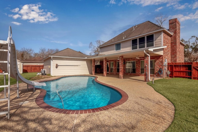 view of pool with a water slide, a patio, and a lawn