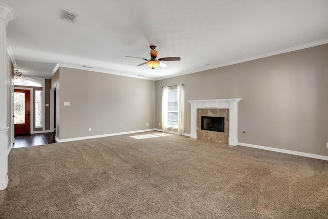 unfurnished living room featuring a premium fireplace, crown molding, ceiling fan, and dark carpet