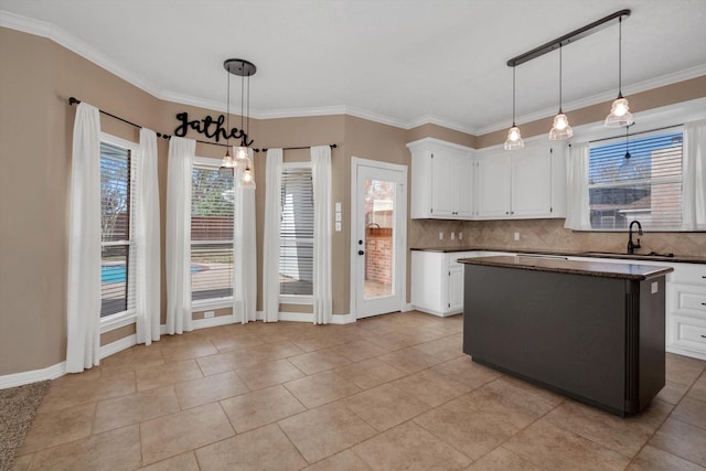 kitchen with sink, white cabinetry, hanging light fixtures, a kitchen island, and decorative backsplash