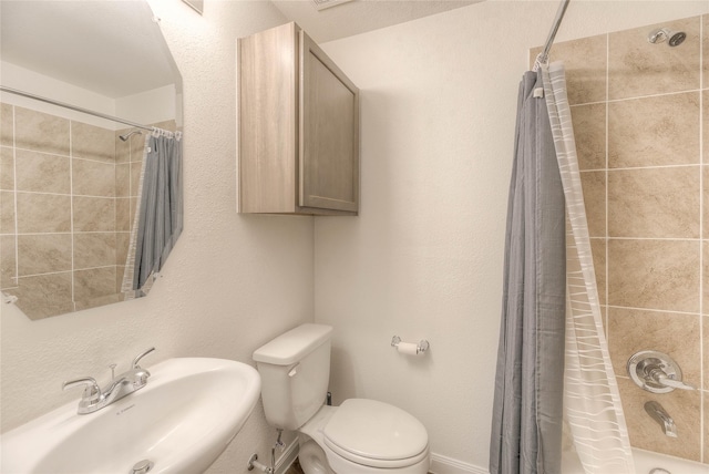 bathroom featuring toilet, shower / bath combo, and a sink