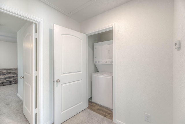 laundry room featuring stacked washer / drying machine, laundry area, and light carpet