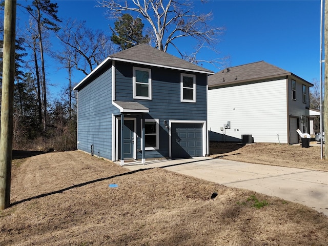 rear view of property featuring concrete driveway, an attached garage, and central air condition unit