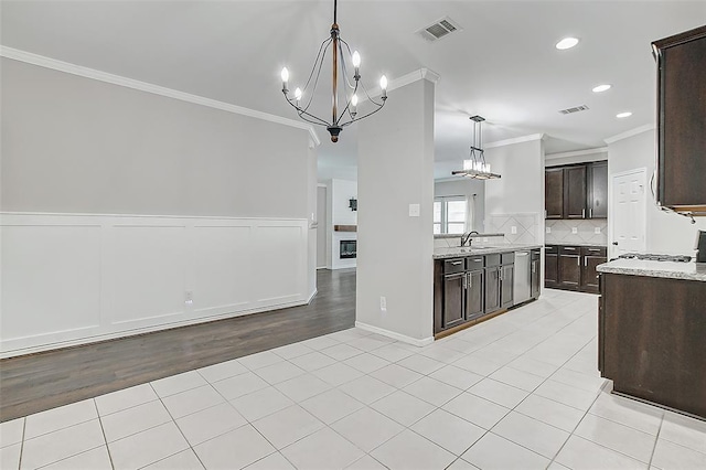 kitchen featuring dark brown cabinetry, sink, decorative light fixtures, and light tile patterned flooring