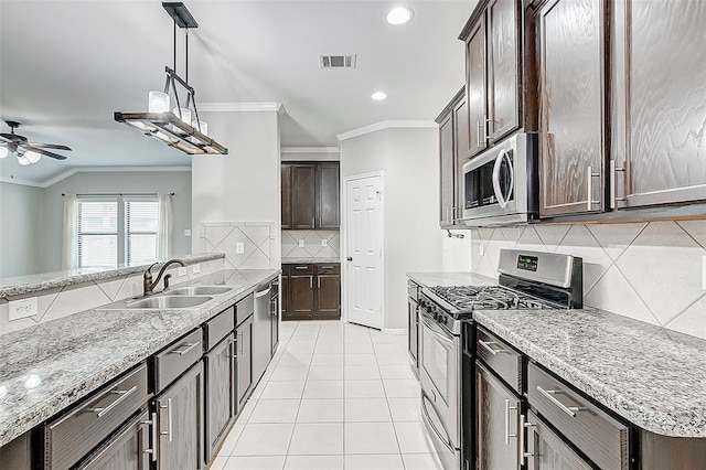 kitchen featuring sink, light tile patterned floors, appliances with stainless steel finishes, hanging light fixtures, and ornamental molding