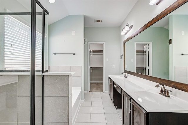 bathroom featuring tile patterned flooring, vaulted ceiling, vanity, and a bathtub