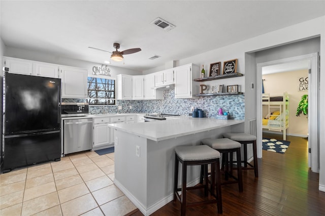 kitchen with a breakfast bar area, white cabinetry, stainless steel appliances, tasteful backsplash, and kitchen peninsula