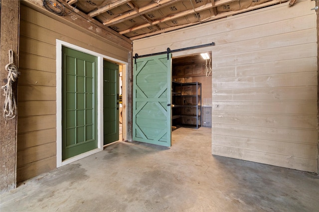 basement featuring wooden walls and a barn door