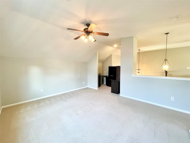 unfurnished living room featuring vaulted ceiling, carpet flooring, a ceiling fan, and baseboards