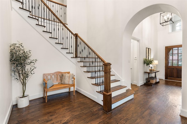 foyer with a notable chandelier, a towering ceiling, and dark hardwood / wood-style floors