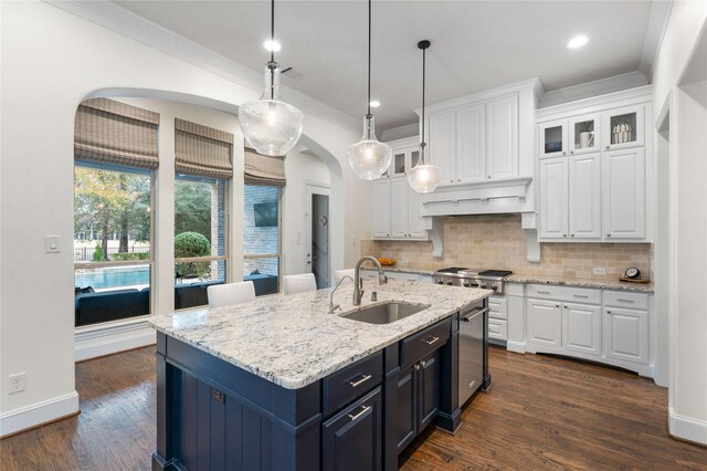 kitchen with dark hardwood / wood-style floors, decorative light fixtures, an island with sink, sink, and white cabinets