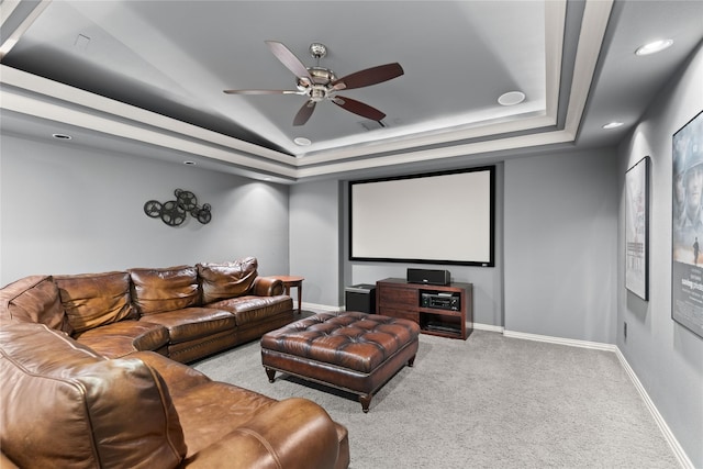 carpeted cinema featuring ceiling fan and a tray ceiling