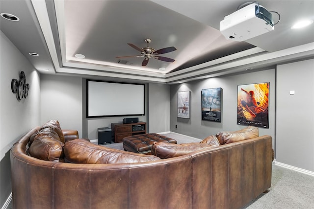 home theater room with light carpet, a tray ceiling, and ceiling fan