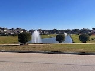 view of community featuring a water view and a yard
