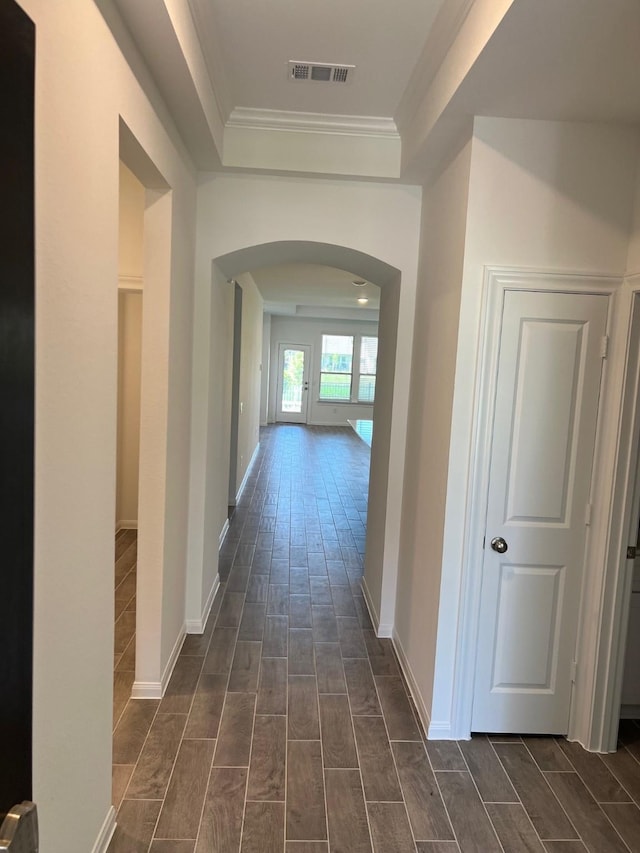 hallway featuring arched walkways, wood finish floors, baseboards, and visible vents