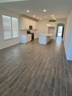 kitchen with white cabinets, arched walkways, light countertops, recessed lighting, and range