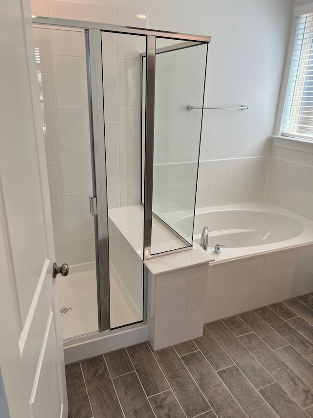 bathroom featuring a shower stall, a bath, and wood finish floors