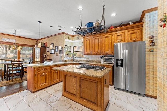 kitchen with light stone countertops, appliances with stainless steel finishes, a center island, and pendant lighting