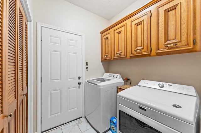 washroom with cabinets, washing machine and clothes dryer, and a textured ceiling