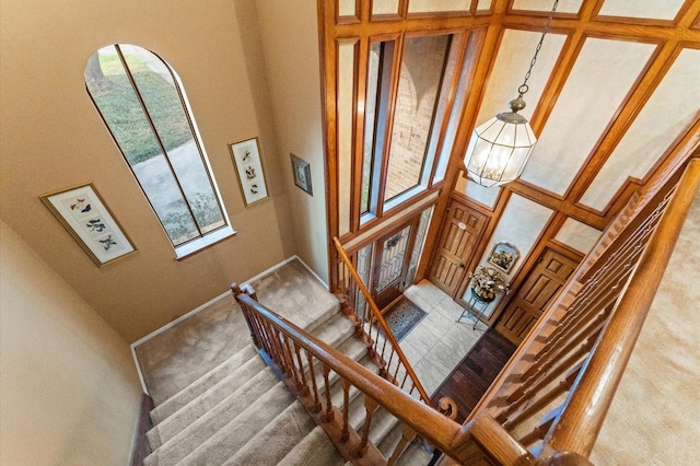 staircase featuring a towering ceiling and a notable chandelier