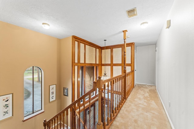 hall with light carpet and a textured ceiling